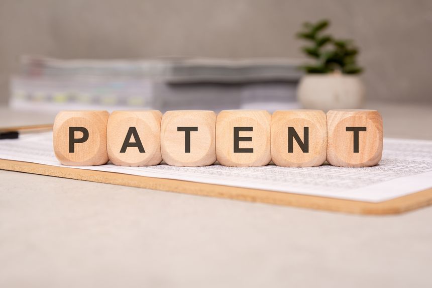 PATENT spelled out with wooden blocks resting on a document sheet, representing innovation, legal rights, and intellectual property protection.