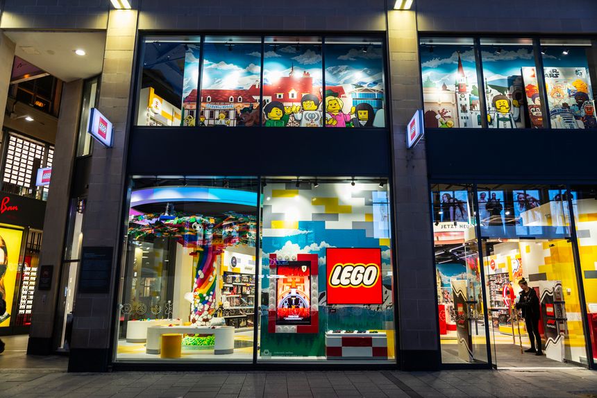 Munich, Germany - April 3, 2025: Lego shop, known for the manufacture of Lego-brand toys, consisting mostly of interlocking plastic bricks, with people around at night in Kaufingerstraße, a shopping street of Munich, Germany