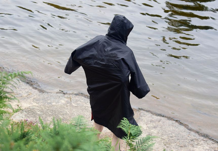 Man in dry changing robe after wild swim outdoors UK