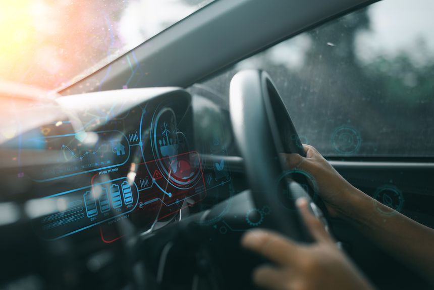 Close-up of hands on steering wheel with futuristic digital dashboard display, showcasing advanced vehicle technology and interface.