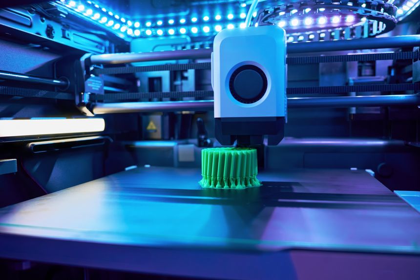 A 3D printer is in action, meticulously producing a vibrant green cylinder with intricate details under bright LED lighting. The workspace features advanced technology, enhancing creativity.