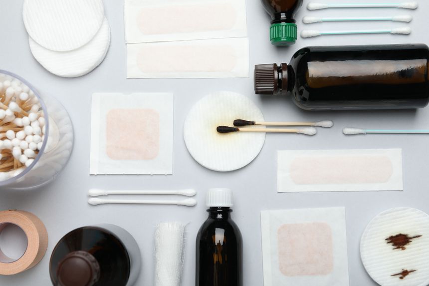 Topical iodine and other first aid kit components on light grey background, flat lay