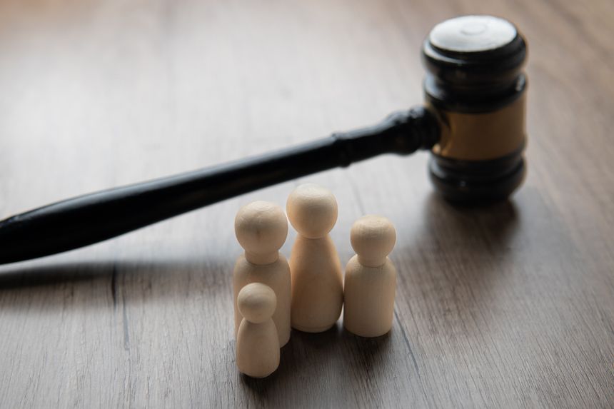 A gavel and four wooden figurines representing a family on a table. Family law concept.