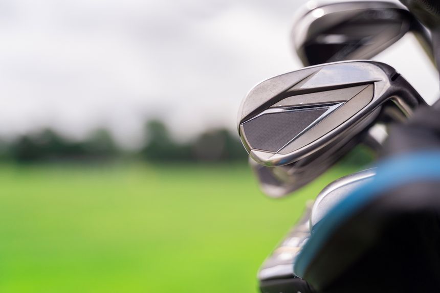 The image shows various golf clubs against a beautifully blurred green landscape, perfect for sports enthusiasts