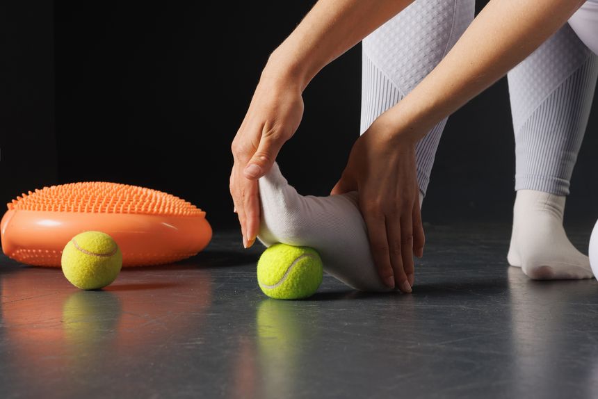 Strengthening the ankle joint with a tennis ball, a therapist is treating the legs, a close-up foot massage