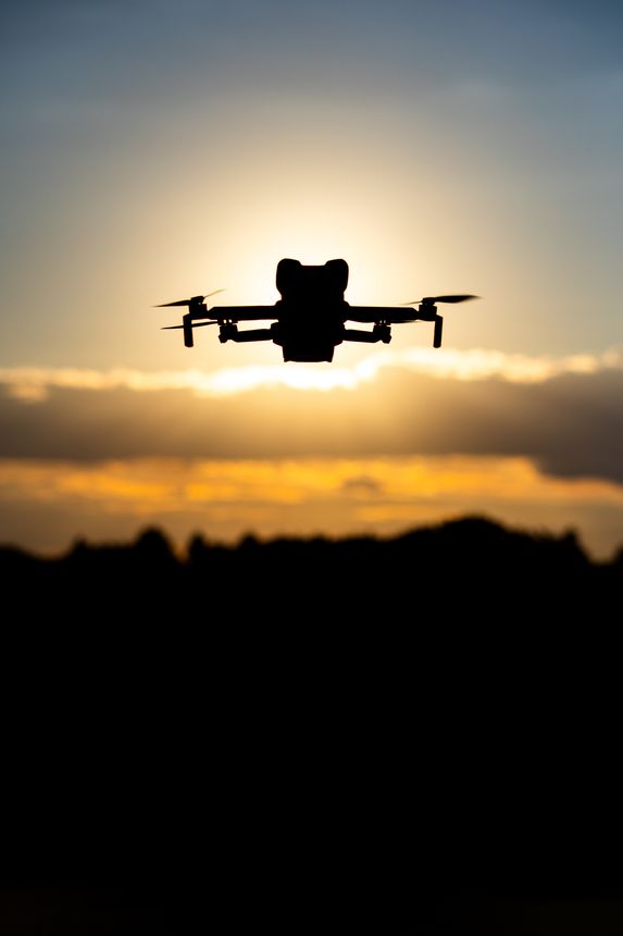 Hamburg, Germany - September 30, 2025: Silhouette of a Drone Flying in the Sky at Sunset with Glowing Sunlight and Scenic Cloudscape in the Background