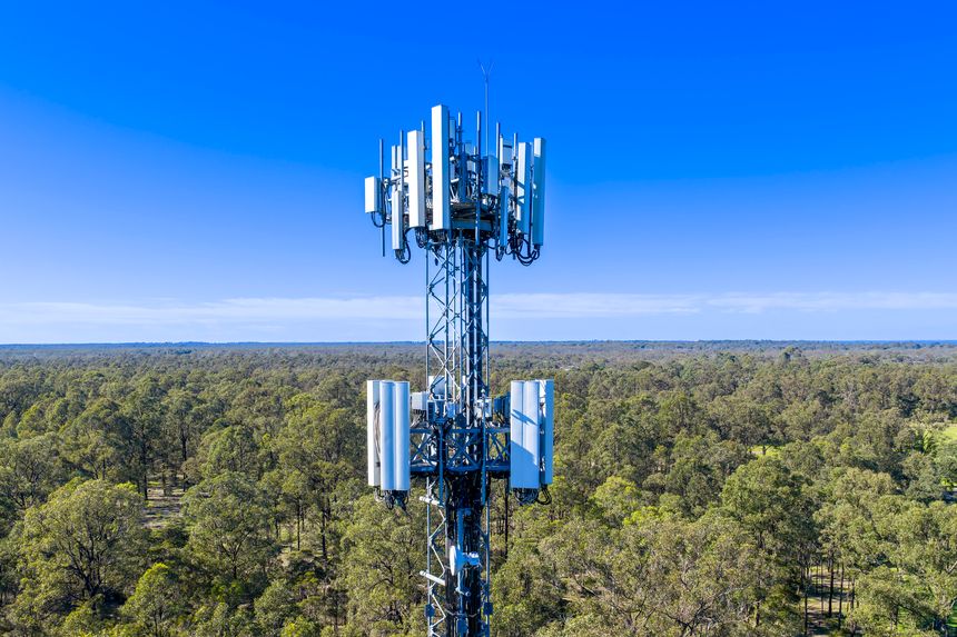 Drone aerial photograph of the top section of a large Telecommunications Tower located in a residential area amongst lush bushland in regional NSW, Australia.
