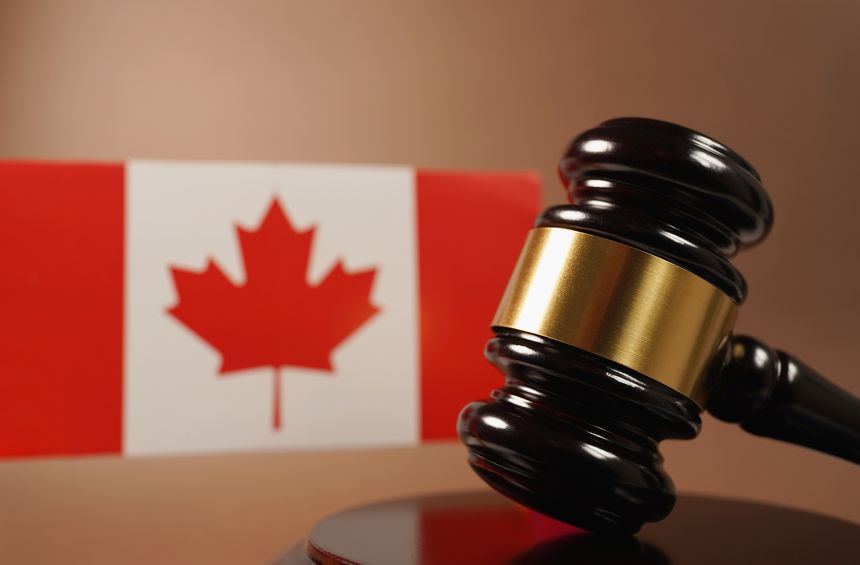 Canada law, legal system and justice concept with a wooden judge gavel and the Canadian flag on background.