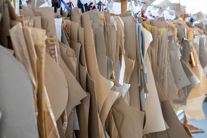 A large collection of paper sewing patterns hanging on a rack in a fashion designer's studio or garment factory. A concept of the clothing industry and dressmaking.