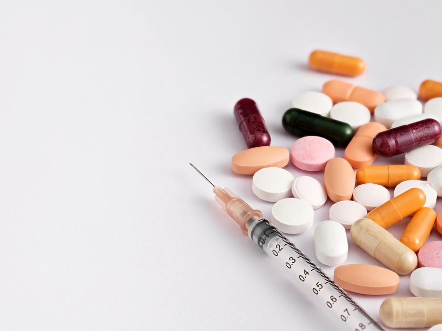 Syringe surrounded by a vibrant assortment of colorful pills, creating a dynamic background for concepts in pharmaceuticals and healthcare