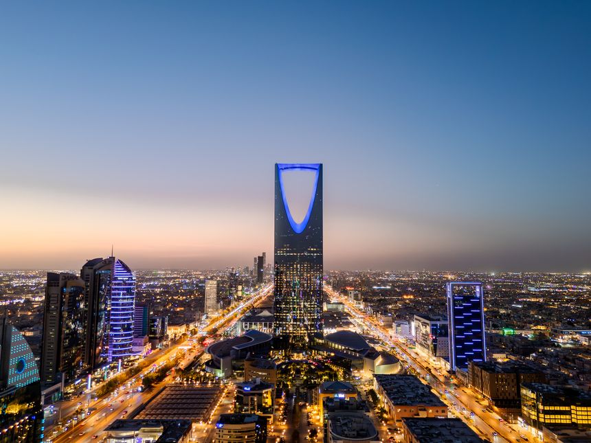 Aerial drone photo captured at dusk in Riyadh, Saudi Arabai. The city begins it's transformation to a brightly illuminated and busy environment with colorful lights and buildings.