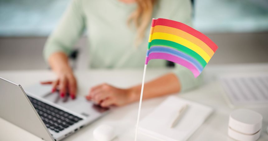 Female Employee Texting In Inclusive Business Office Supporting LGBTQ Equality