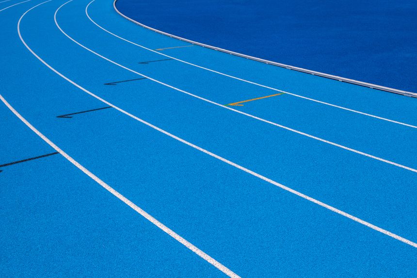 Blue Olympic track lanes with white stripes, an empty background suitable for copy space, represent the concept of physical sports and running, symbolizing commitment and pathways towards goals