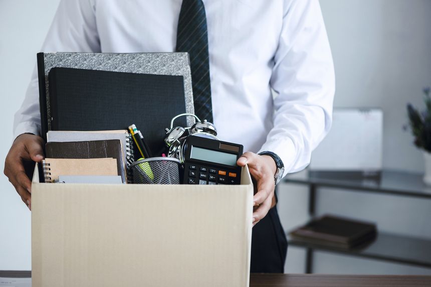 Businessmen hold boxes for personal belongings and resignation letters for resign by the desk in the office for changing and resigning from work concept for quit or change of job