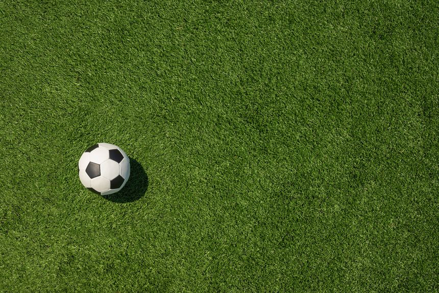 Soccer ball on field and artificial green grass. Football stadium background. View from above. Space for design.