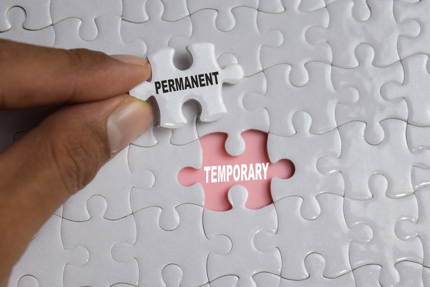 Hand holding piece of jigsaw puzzle with word Permanent temporary. Business and finance concept