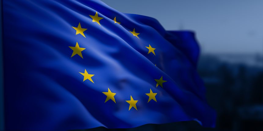 European Union flag with golden stars waving on dynamic blue fabric in front of a blurred cityscape background. Concept of unity and international cooperation. 3D Rendering