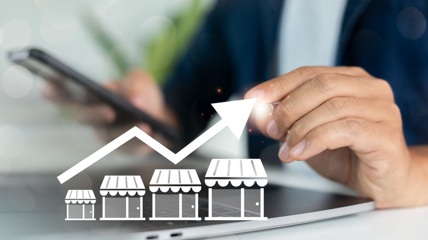 Close-up of a hand using a smartphone with increasing store graph icons, representing franchise business growth, retail expansion, and multi-location store strategy.