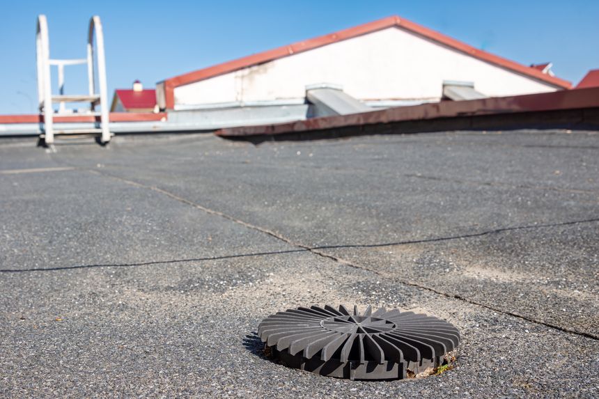 A damaged rainwater drain grate on a rooftop, representing the consequences of neglect and inadequate maintenance that compromise building integrity and safety with selective focus on the grate