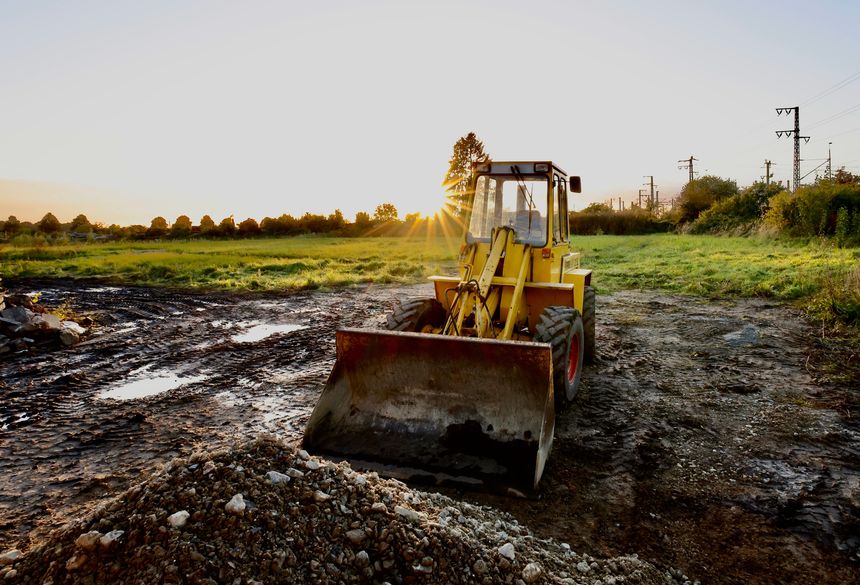 A loader equipment on a field against a bright sunny background