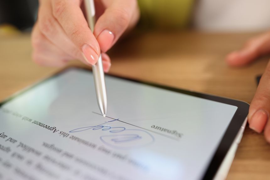 Close-up of female hand signing e-document on tablet with stylus. Electronic signature and modern technologies concept