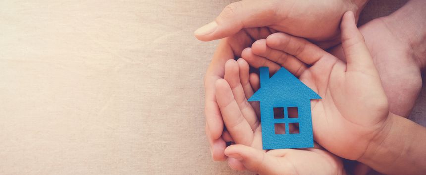 Adult and child hands holding blue paper house for family home and homeless shelter concept