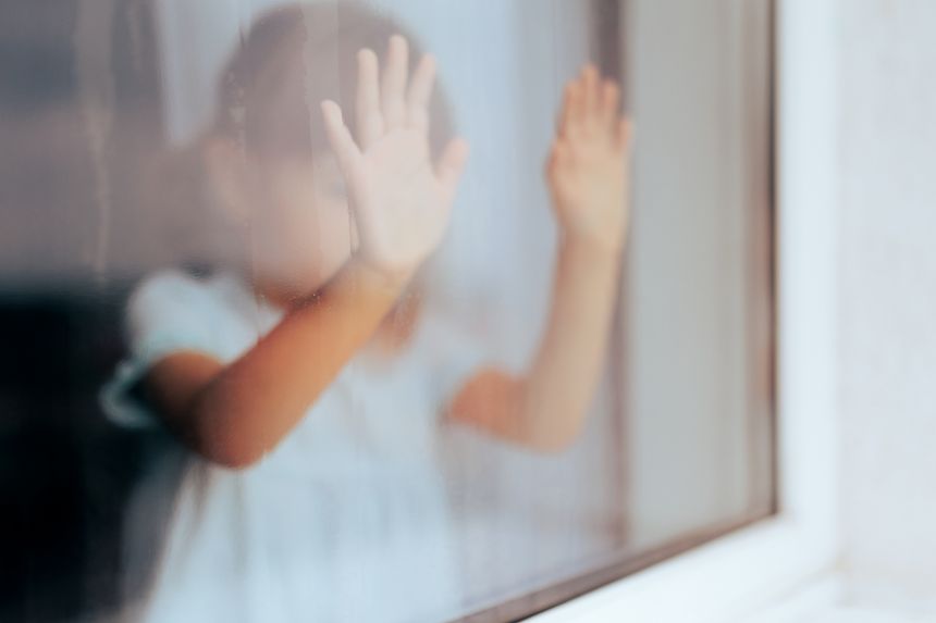 Unhappy child looking through the window feeling anxious and depressed