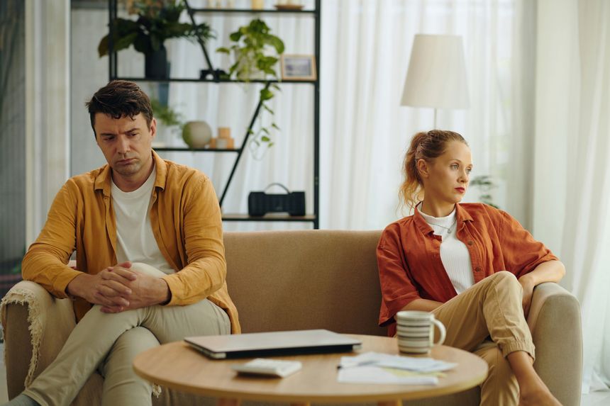 Couple sitting on sofa in conflict in the living room