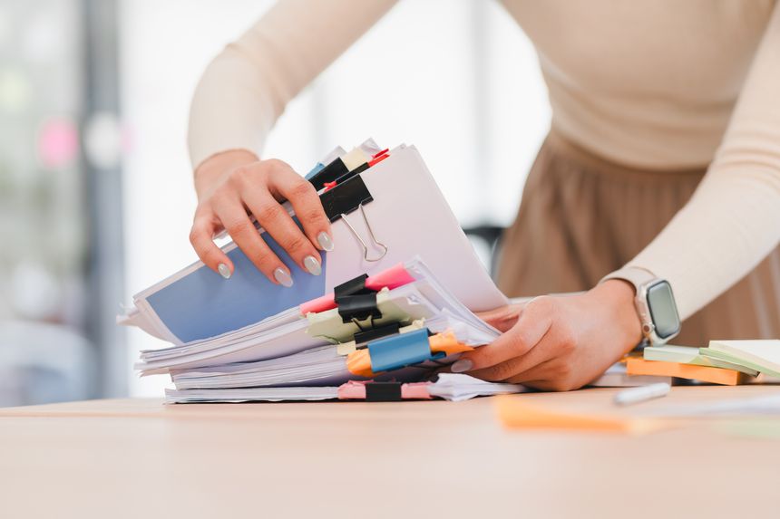 A person organizing stacks of documents with colorful clips on desk, showcasing productivity