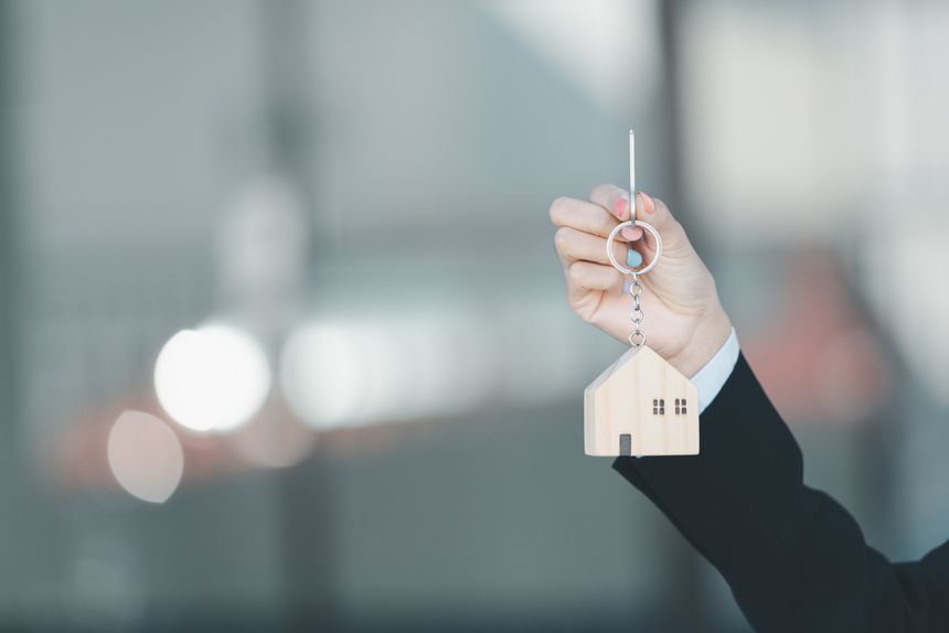 Woman hand hold key buy home model business concept involves sell financial management investment bank loan ownership income economy finance investments purchasing apartment blur background estate