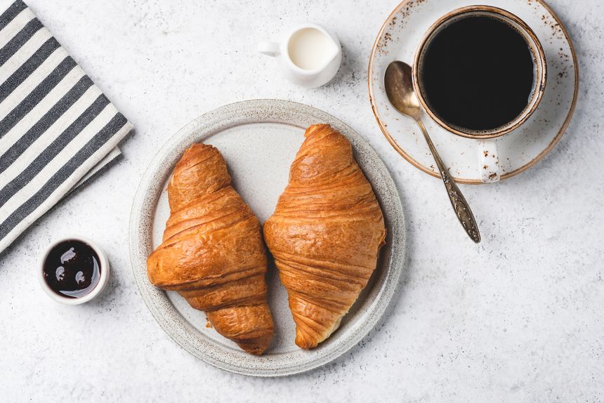 French croissants, jam and cup of coffee on grey concrete table background, top view