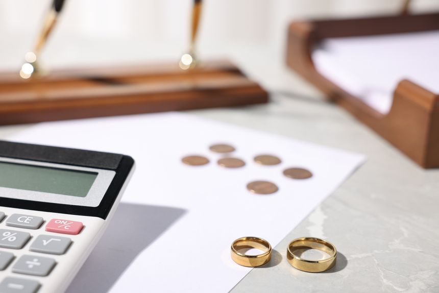 Alimony. Wedding rings, coins, documents and calculator on grey marble table, closeup