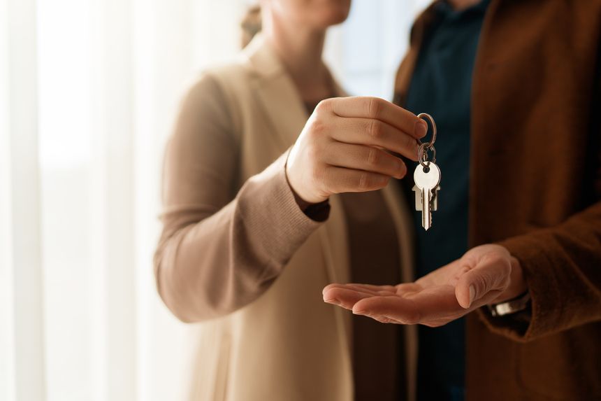 Real estate agent gives house keys to new homeowner. Property deal, mortgage loan