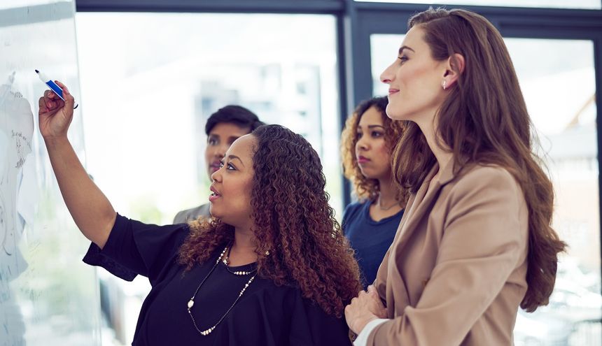 Cropped shot of a group of businesswomen working on a whiteboard in the boardroom