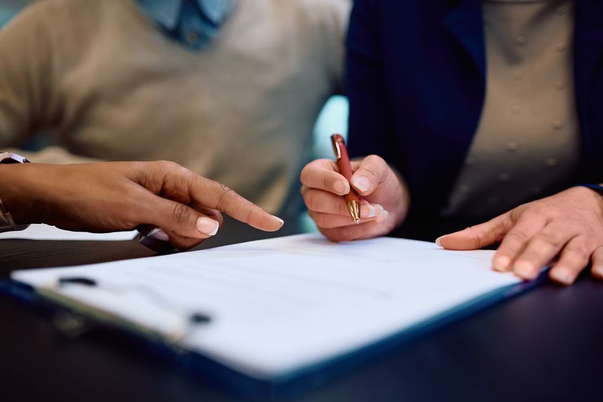 Close up of couple signing contract with bank manager in the office.