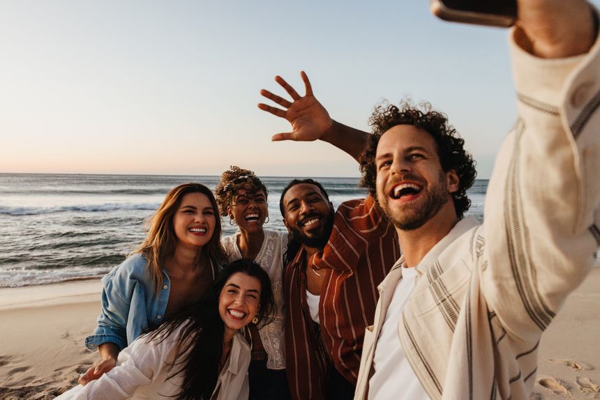 A cheerful group of friends gathers on the beach, sharing a joyful moment together.