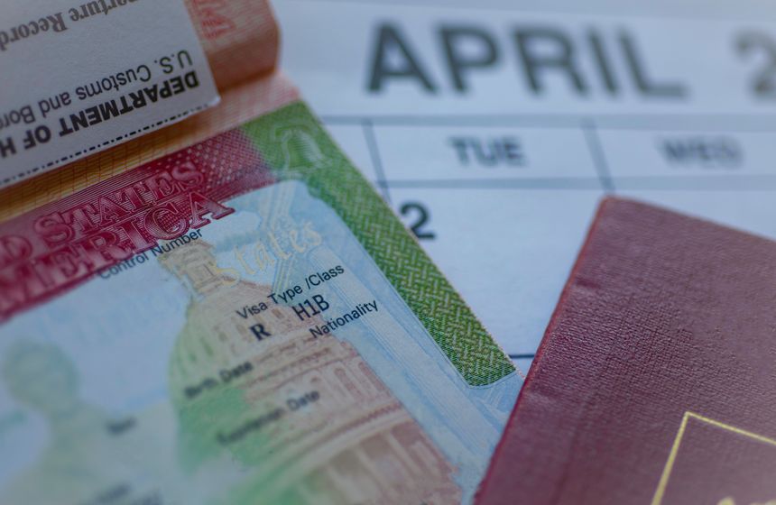 H1B visa (for specialty workers) stamp in passport, blurred april calendar on background. H1B visa program deadline concept. Close up view.