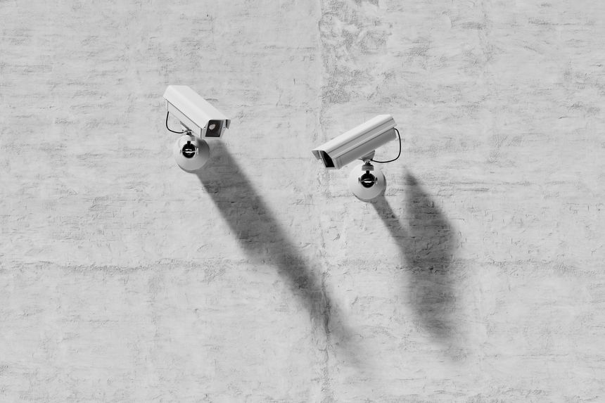 two outdoor video surveillance cameras on a concrete wall, security system