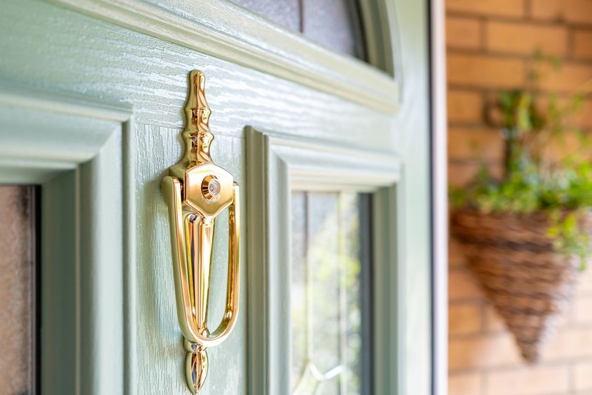 The focus is on the brass door knocker with an internal peephole.