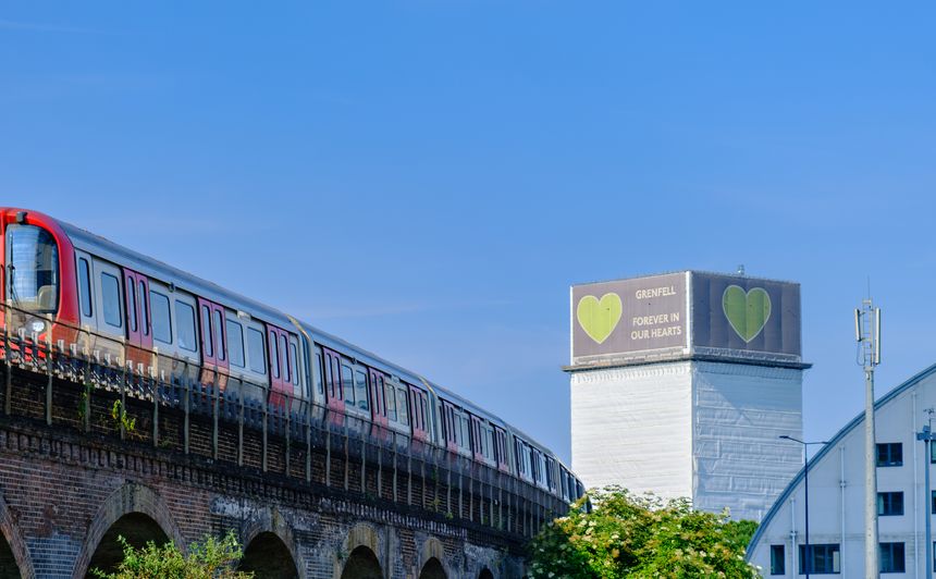 London, England - June 15, 2023: A train passes in North Kensington with the Forever in our hearts support banner visible on the Grenfell tower in the background