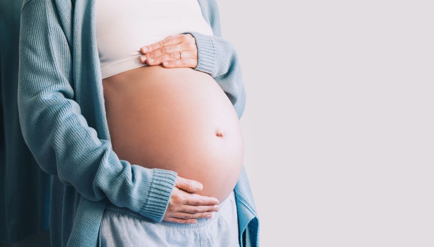 Beautiful pregnant woman holds hands on her belly. Happy mother waiting for baby birth. Pregnancy, maternity, preparation and expectation concept.