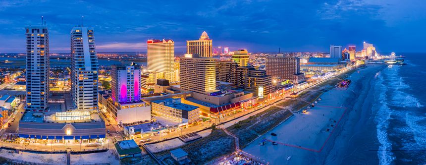 Aerial panorama of Atlantic City along the boardwalk at dusk. In the 1980s, Atlantic City achieved nationwide attention as a gambling resort and currently has nine large casinos.