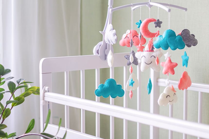 Baby crib mobile with stars, clouds and moon. Kids handmade toys above the newborn crib. First baby eco-friendly toys made from felt hanging in light room.