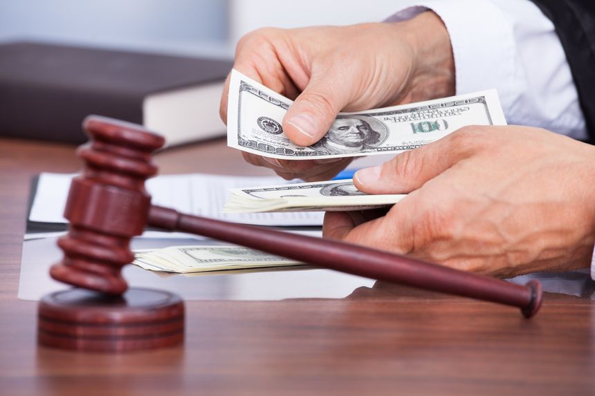Close-up Of Male Judge's Hand Counting Banknote In Front Of Mallet