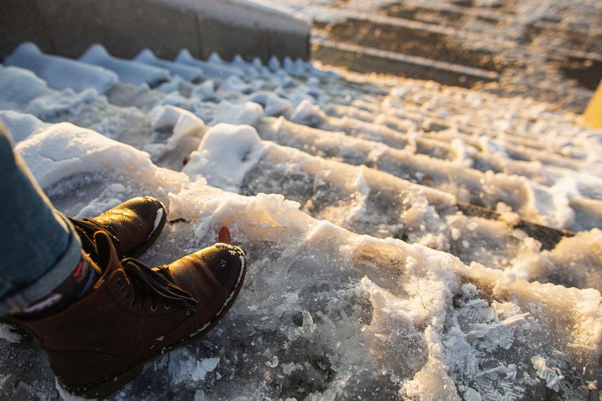 Danger of slipping. Female boots on rough slipper ice surface. A woman in brown leather shoes descends the slippery ice ladder.