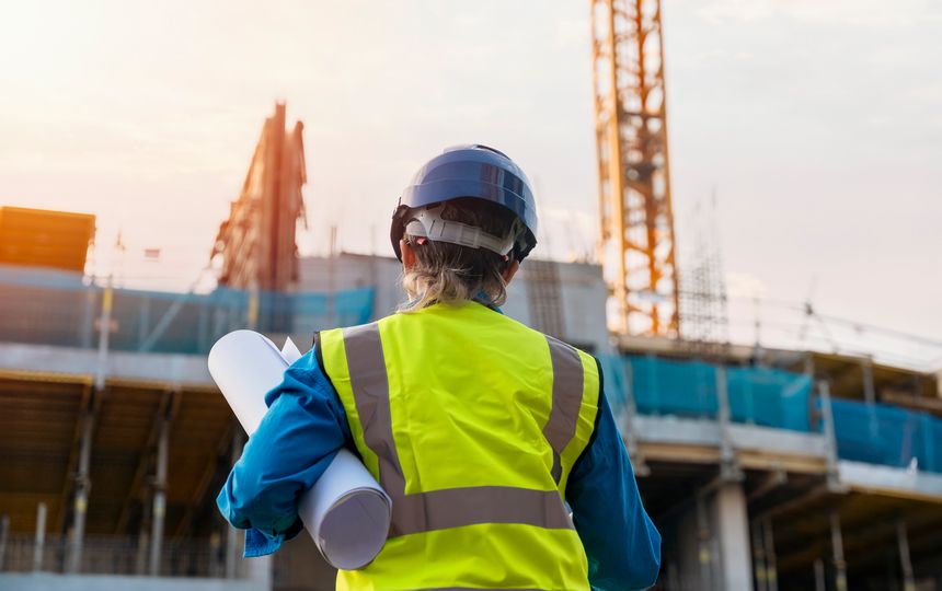 Female site engineer surveyor working with theodolite total station EDM equipment on a building construction site outdoors