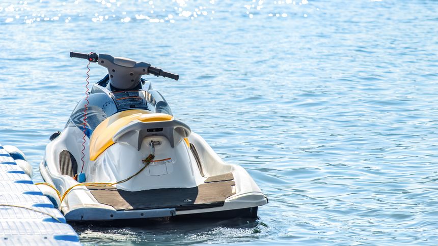 Jet ski tied by a rope to a modular floating plastic pontoon berth at seaside resort