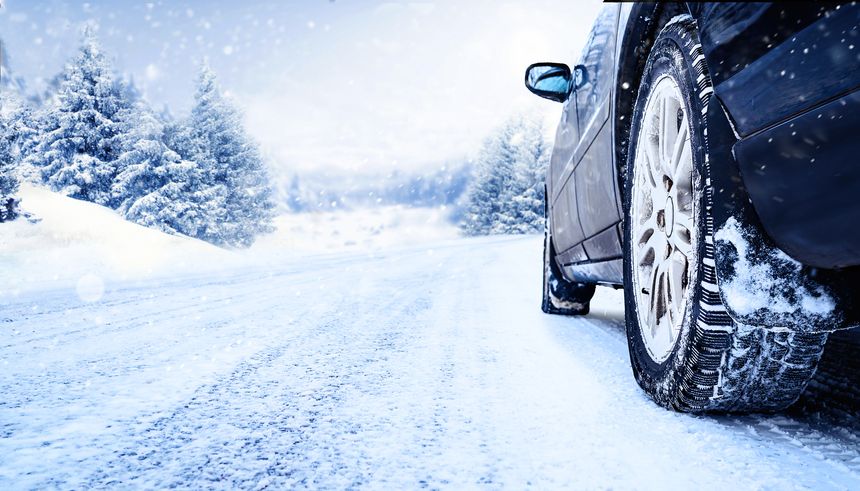 Winter tire closeup. Car on snowy road with beautiful landscape.