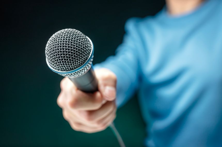 Hand holding and recording interview with microphone conducting an interview or press conference