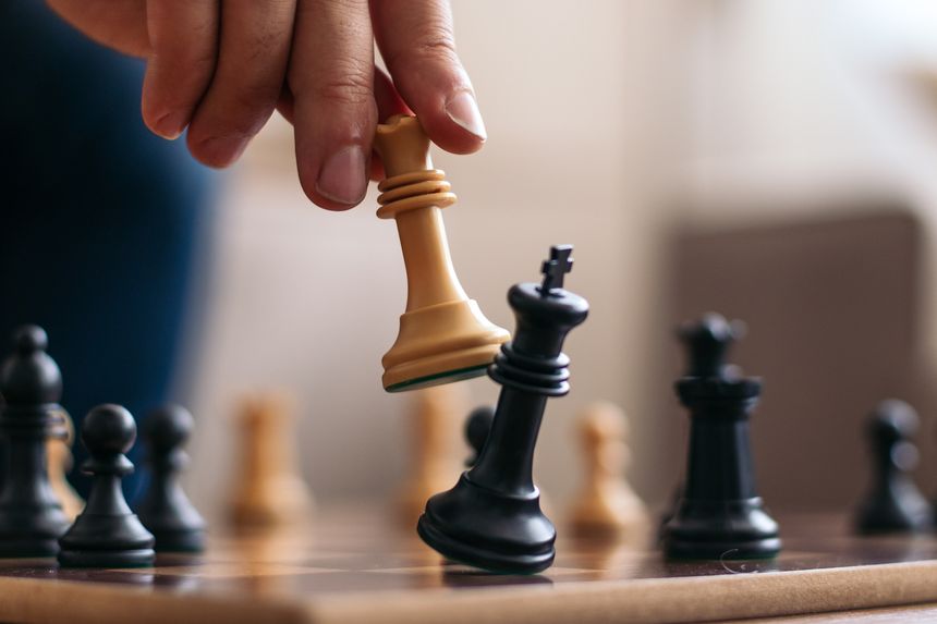 Checkmate. Hand of an unrecognizable man playing chess defeating his opponent's king